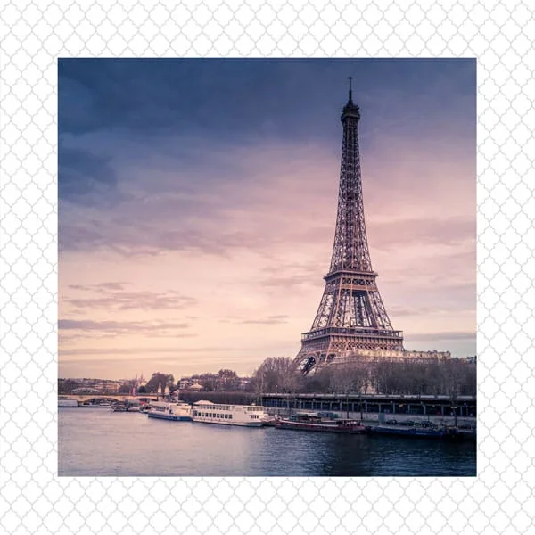 Torre Eiffel em Paris ao entardecer, símbolo icônico da França, vista pela margem do rio Sena.