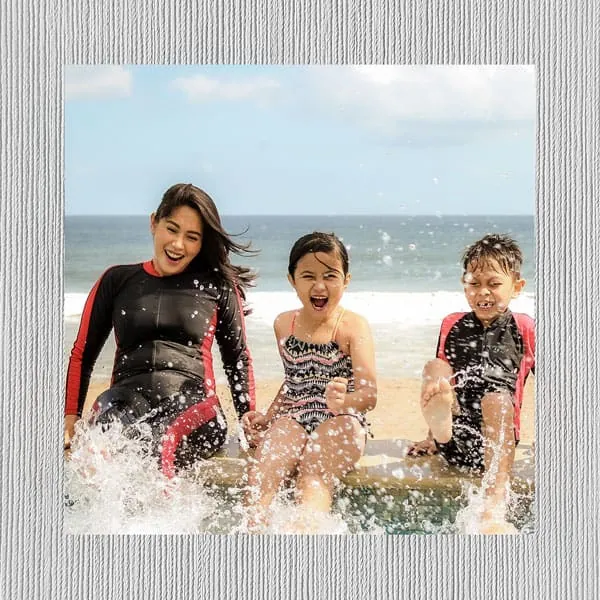 Alegria de crianças na praia com roupas esportivas Uniko, momento divertido ao ar livre; moda infantil confortável e estilosa.