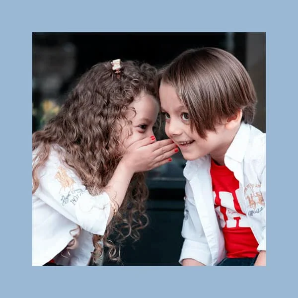 Crianças conversando secretamente, momento de diversão e amizade, estilo casual e natural.