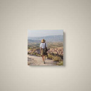 Mulher caminhando por trilha em cenário de tirar o fôlego com natureza e montanhas ao fundo.